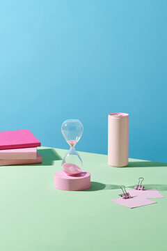  Aesthetic workspace set up with pink hourglass, notebook, pen.
