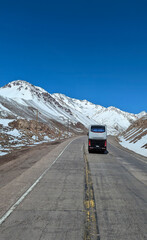 Bus on mountain road in winter. No logo and no brand on bus. Road in the Andes mountains between Mendoza, Argentina and Santiago, Chile.