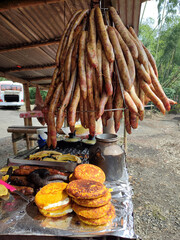 Latin roadside sale with hanging chorizos and corn arepas or sweet cob