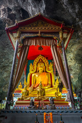 The large Buddha gold statue inside the cave at Wat Ban Tham, Kanchanaburi, Thailand