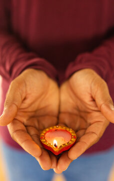 Holding lit diya, person celebrating traditional Indian diwali festival at home, copy space
