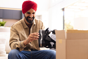 Smiling man unpacking VR headset from cardboard box at home