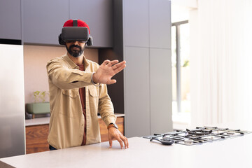 Using VR headset, man interacting with virtual environment in modern kitchen, copy space
