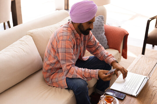 Using laptop and holding credit card, man shopping online from home