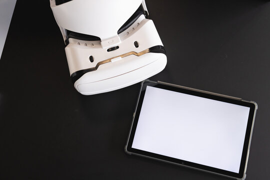 Virtual reality headset and tablet on black desk for business presentation, copy space