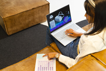 Using laptop, woman analyzing virtual reality data and pointing at chart in office