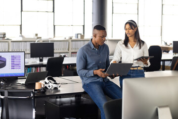 Collaborating in office, colleagues using laptop and tablet for project discussion