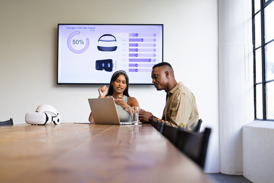 Discussing business strategy, colleagues using laptop and VR headset in meeting room, copy space