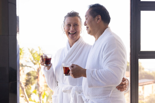 Senior couple in bathrobes enjoying coffee together, smiling and relaxing - Powered by Adobe
