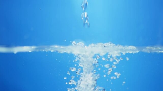 Pouring droplets of crystal clear water into a container creating ripples and waves.