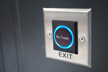 Close up of an exit button on a hardwood door in electric blue font
