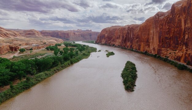 Colorado River, canyon, green trees and buttes in Moab, Utah, United States of America.