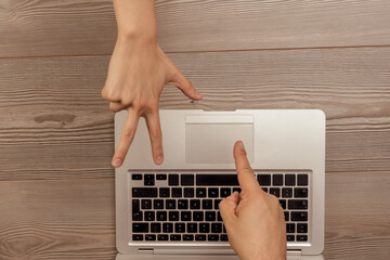 Hands playing morra above laptop, online gambling