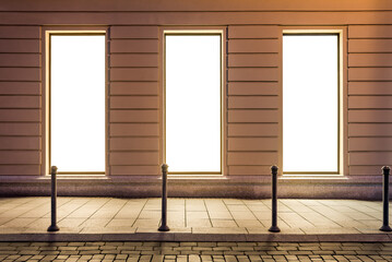Mockup Of Three Empty Showcase Windows In City Street At Night. Illuminated Blank Space For Your Commercial