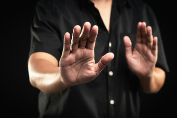 Obraz premium Person shows a stop gesture while standing on a black background.