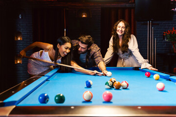 Young diversity group of people playing pool together with smile, enjoyment and fun. Young people...