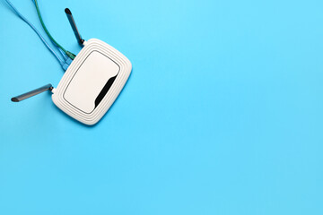 Modern wi-fi router with cables on blue background