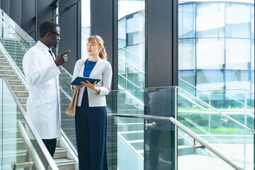 A group of businessmen and multinational engineers in white coats having a conversation in the lobby