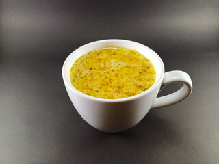 Rich beef steak sauce presented in a white glass cup against a dark grey ash background, highlighting the deep, savory flavors in a simple yet elegant setting