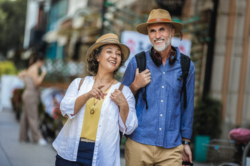 Elderly married couple walking through the new city with backpacks.