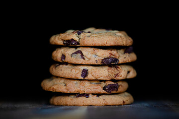 A stack of chocolate chip cookies against dark background