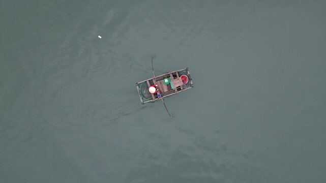 aerial shot of woman rowing her boat through floating fishing village in Cat Ba and Halong Bay in Northern Vietnam