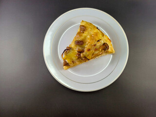 Cheesy and Meaty Pizza on Small White Plate Against Dark and Ash Abstract Background: Enjoy a Savory Delight with Melted Cheese and Flavorful Meat, Perfectly Presented for Your Culinary Pleasure