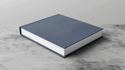 A minimalist hardcover book with a blue cover, lying closed on a concrete surface, representing simplicity and modern design.