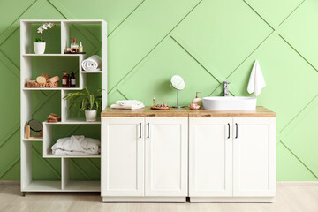 Chest of drawers with sink and bath supplies in stylish interior of bathroom