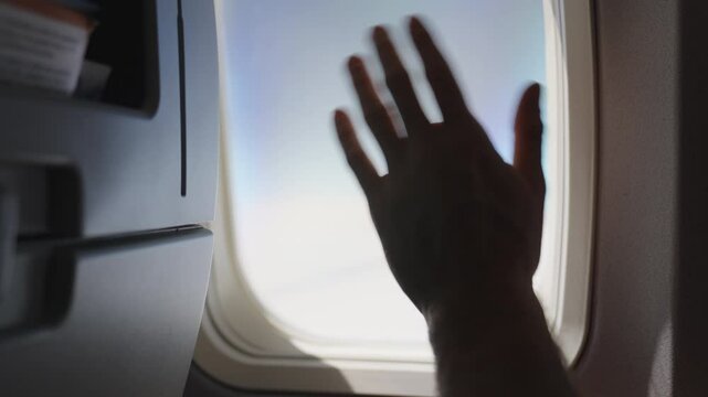 waving goodbye from inside an airplane through the plane's window. Emotional farewell as the aircraft prepares for departure. Perfect for themes of travel, separation, and heartfelt goodbyes."