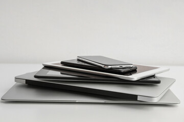 Stack of different modern gadgets on light background