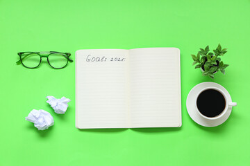 Notebook with text GOALS 2025, cup of coffee and eyeglasses on green background