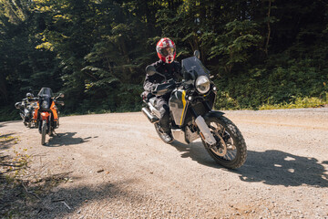 Modern adventure motorcycle on a ride on gravel surface. Motorcycling in nature or offroad, enjoying freedom. Motorbike in the woods. Bike on a bend