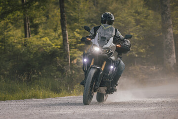 Modern adventure motorcycle on a ride on gravel surface. Motorcycling in nature or offroad, enjoying freedom. Motorbike in the woods. Making a turn © Anze