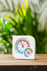 White Thermometer and Hygrometer on Wooden Surface With Green Plant Background