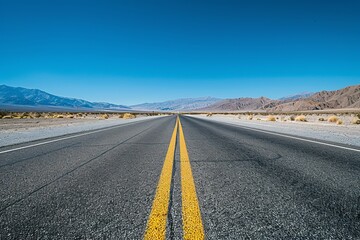 Naklejka premium A panoramic view of a straight, empty asphalt road stretching through a vast desert landscape with mountains in the distance
