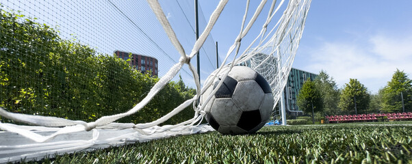 Soccer football in Goal net with green grass field. For sport concept.