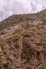A rocky mountain with a cloudy sky in the background
