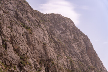 A rocky mountain with a cloudy sky in the background