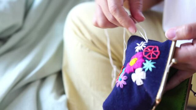 Young woman embroidering handmade picture flower on clasp coin purse. Handicraft, hobby, diy for decoration home concept