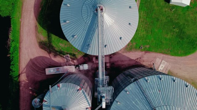 Amazing top down aerial of grain elevator in Wisconsin Rapids, WI where semi trucks loading with grain including soybeans, corn, wheat, and oats. Hopper trailer type.