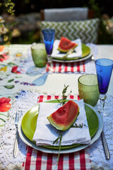 A bright, festive outdoor garden setting in a yellow and red palette with wildflowers, berries and watermelon
