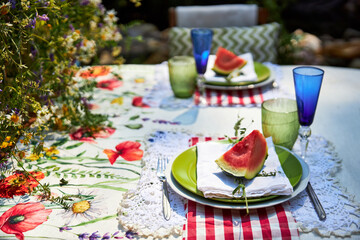 A bright, festive outdoor garden setting in a yellow and red palette with wildflowers, berries and watermelon