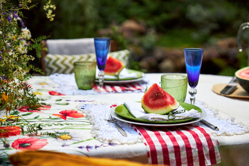 A bright, festive outdoor garden setting in a yellow and red palette with wildflowers, berries and watermelon