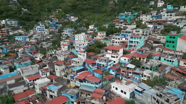 Arcing aerial flyover of colorful hillside buildings in Guatemala town
