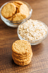Tasty oatmeal cookies and rolled oat on wooden table.