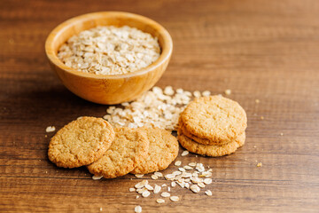 Tasty oatmeal cookies and rolled oat on wooden table.