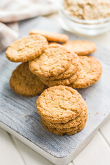 Tasty oatmeal cookies on cutting board on white table.