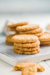 Tasty oatmeal cookies on cutting board on white table.