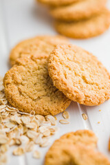 Tasty oatmeal cookies and rolled oat on white table.